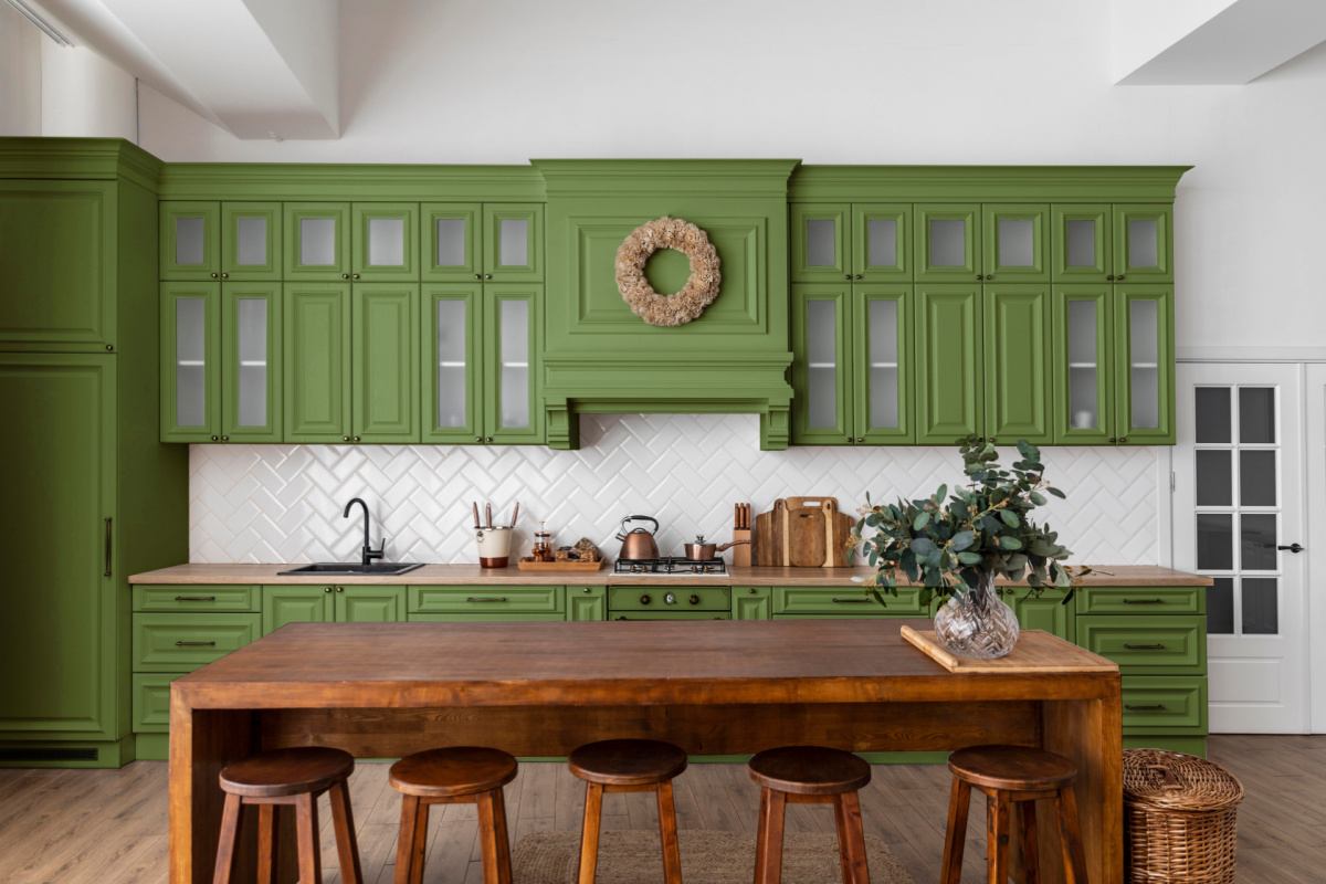 A kitchen with a wood table, wooden chairs, and green cabinetry.